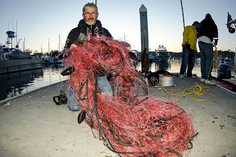 Captain Dave holds up gillnet removed from entangled gray whale