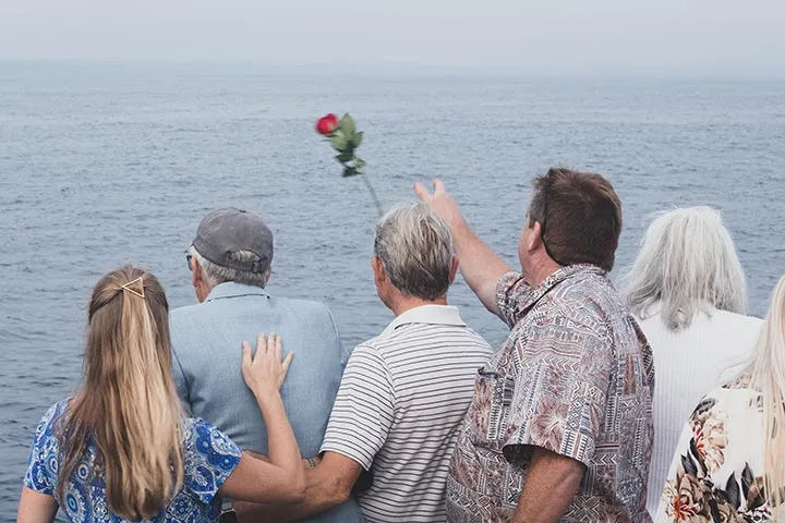 People throwing roses into ocean during burial at sea