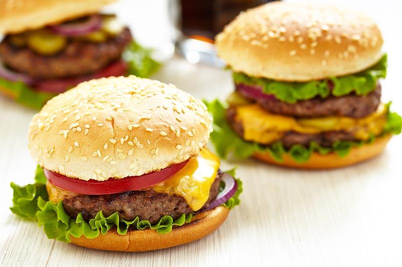 close up of two cheeseburgers with lettuce and tomato