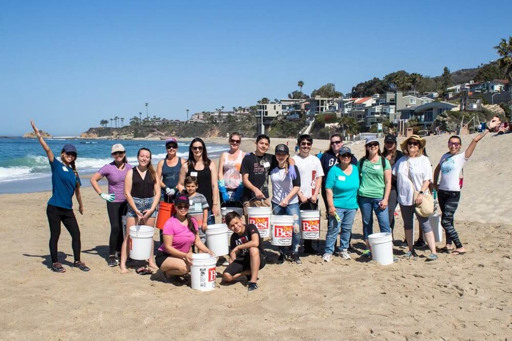 Dolphin-Safari-Aliso-Creek-Beach-Cleanup a group of people standing on top of a sandy beach