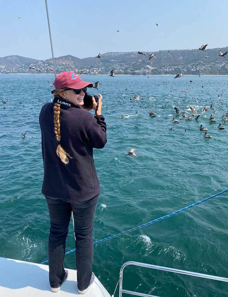 Marine naturalist taking photos from boat during marine tour