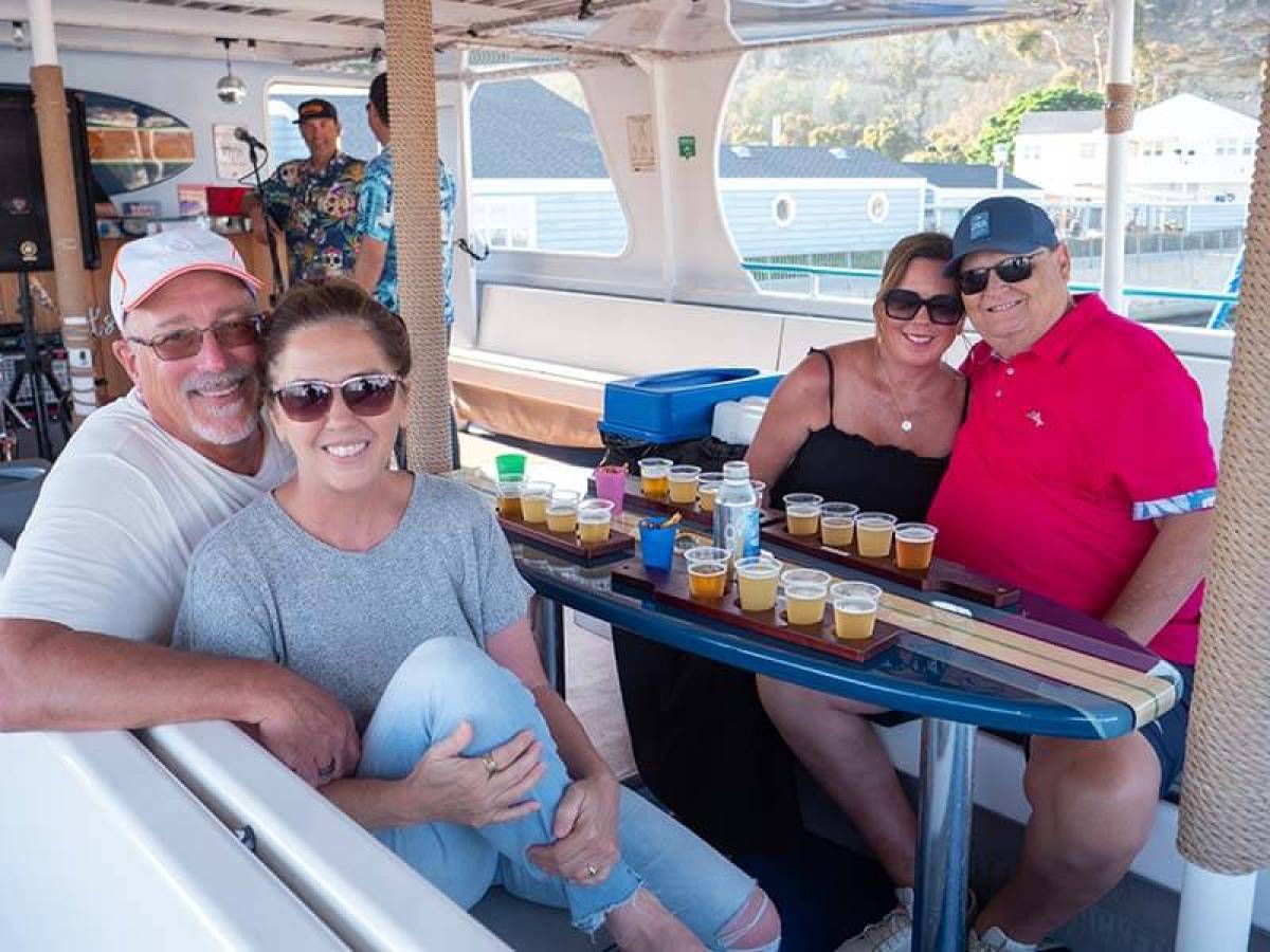 Guests seated at a surfboard table during Brews Cruise beer tasting experience in Dana Point