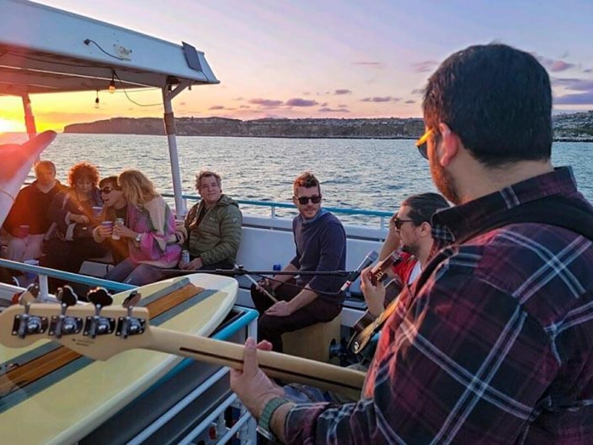Passengers listen to live music during sunset harbor cruise on Hoku Nai'a