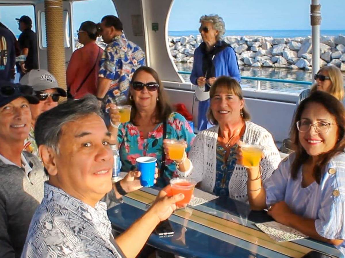 Group of people smiling and holding drinks on Hoku Nai'a in Dana Point Harbor.