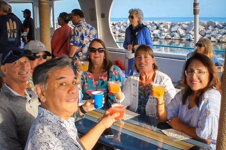 Group of people smiling and holding drinks on Hoku Nai'a in Dana Point Harbor.