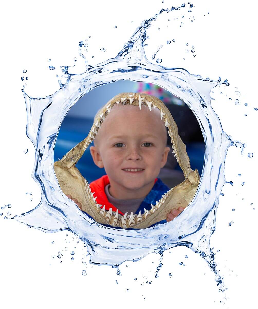 Child's face inside shark jaws with a water splash effect around.