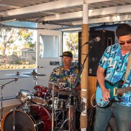 Three band members of Entropy play music on a party boat in Dana Point Harbor