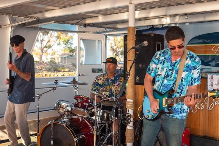 Three band members of Entropy play music on a party boat in Dana Point Harbor