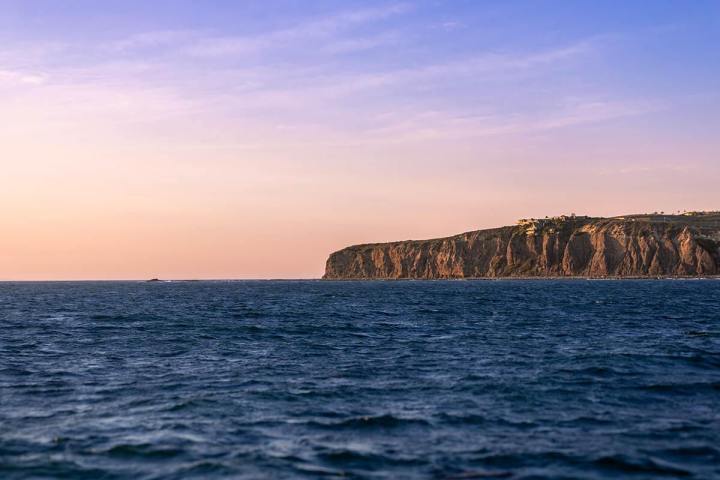 Soft hues of sunset light up the headlands landmark off of Dana Point, California